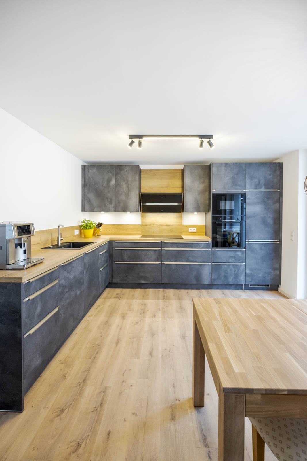 Moderne Artego-L-Küche in dunkler Spachteloptik mit Arbeitsplatte in Eiche Goldbraun und Edelstahl-Griffleisten