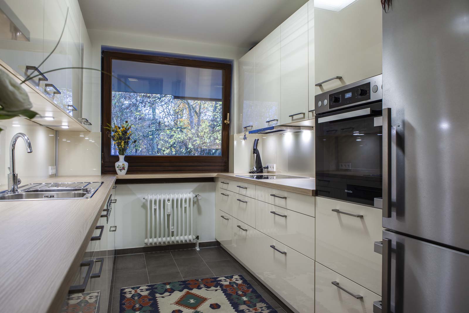 Zweizeilige Küche in Magnolia Hochglanz-Lack mit Backofen-Hochschrank und Blick zum Fenster