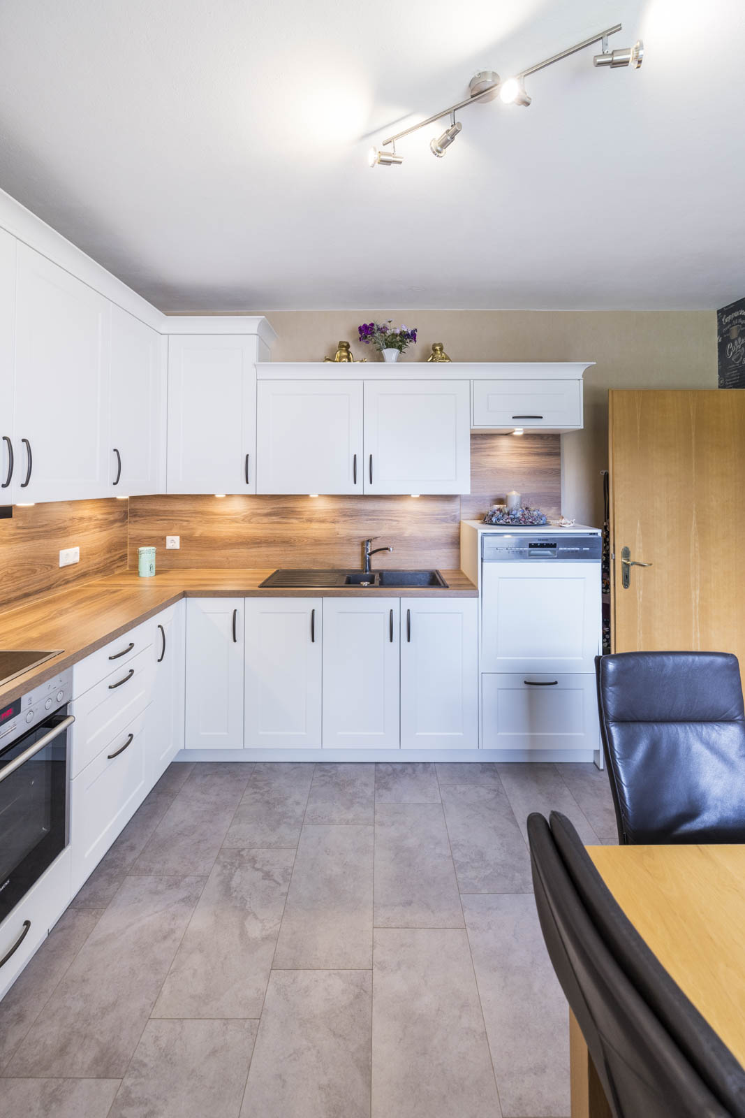 Arbeitsplatte und Nischenrückwand in Eiche Cognac mit schwarzer Spüle in der weißen L-Küche