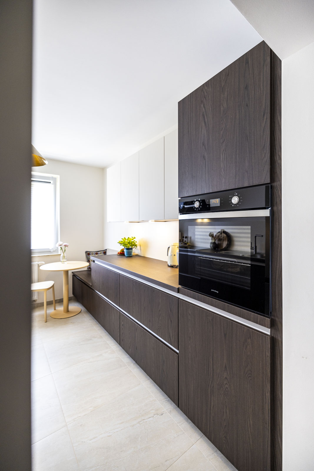 Blick entlang der grifflosen Küchenzeile mit Schubladen, Hochschrank und Backofen