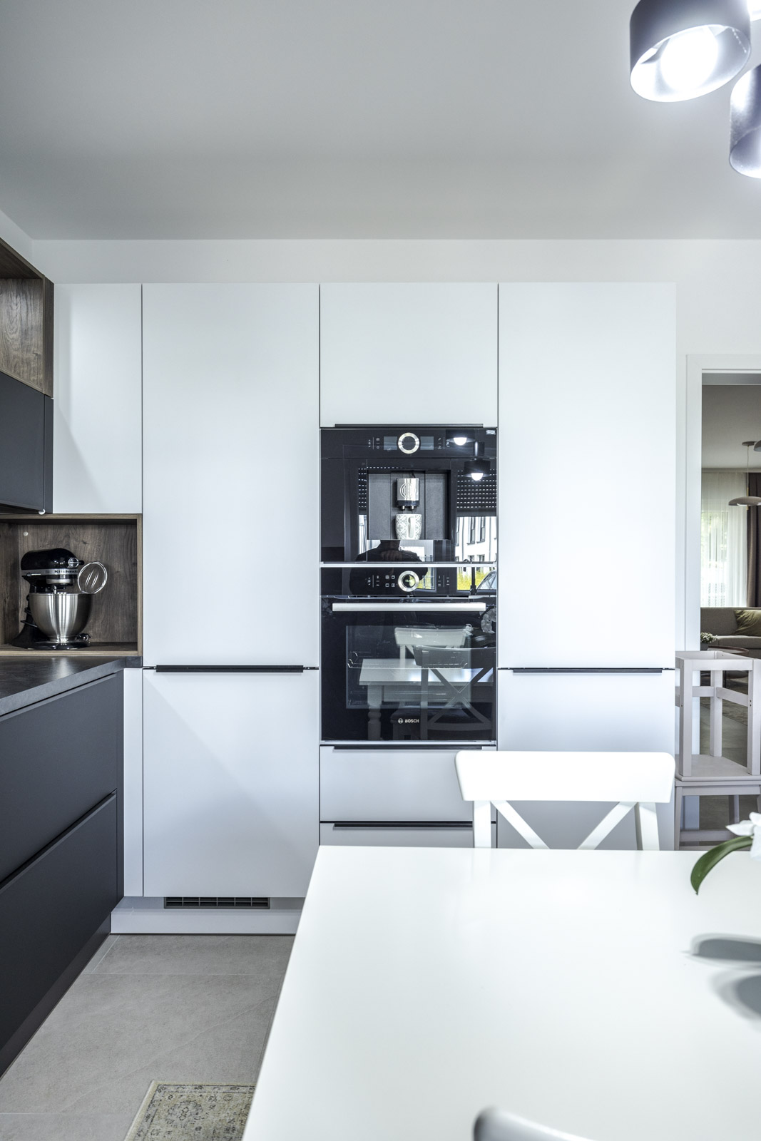 Weiße Schrankwand mit Griffleisten und eingebautem Bosch-Kaffeevollautomat und Backofen