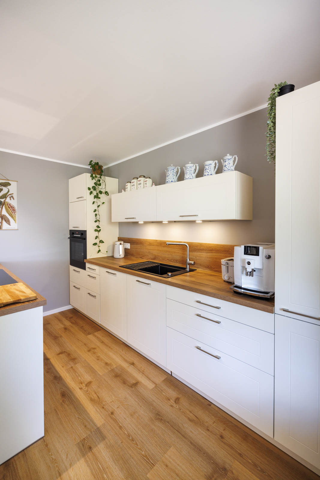 Küchenzeile in Magnolia mit LED-Unterbauleuchten, Hochschränken und Kaffeeecke