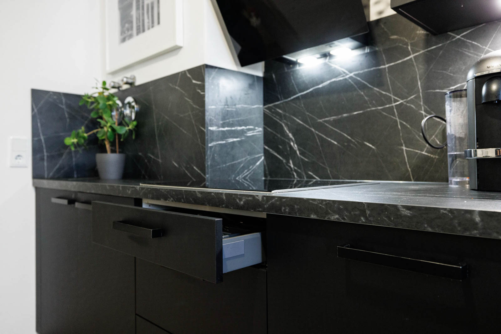 Matte schwarze Lackfront mit schwarzem Bügelgriff und geöffneter Schublade