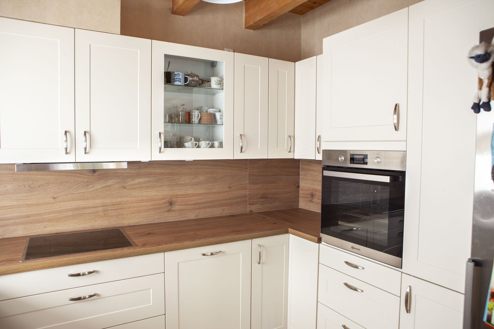 Helle Rahmenfronten Contura in Magnolie mit Glashängeschrank und hochgebautem Backofen