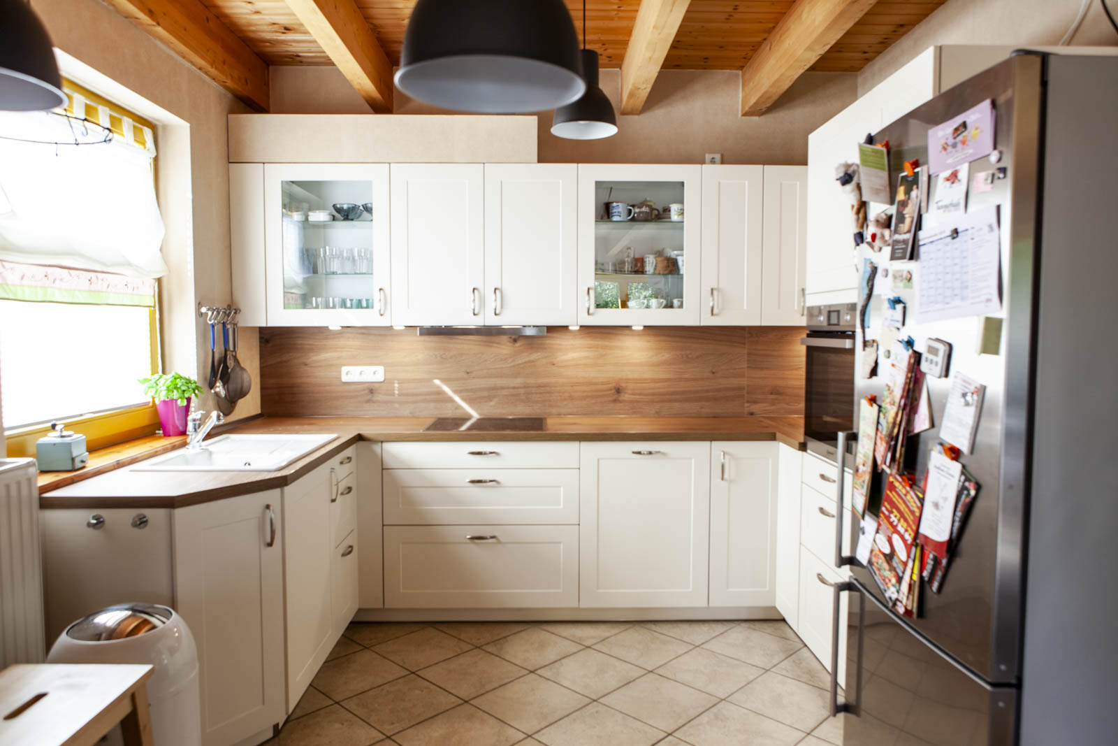 U-Küche in Magnolie mit Glashängeschränken, LED-Unterbauleuchten und Holzbalkendecke