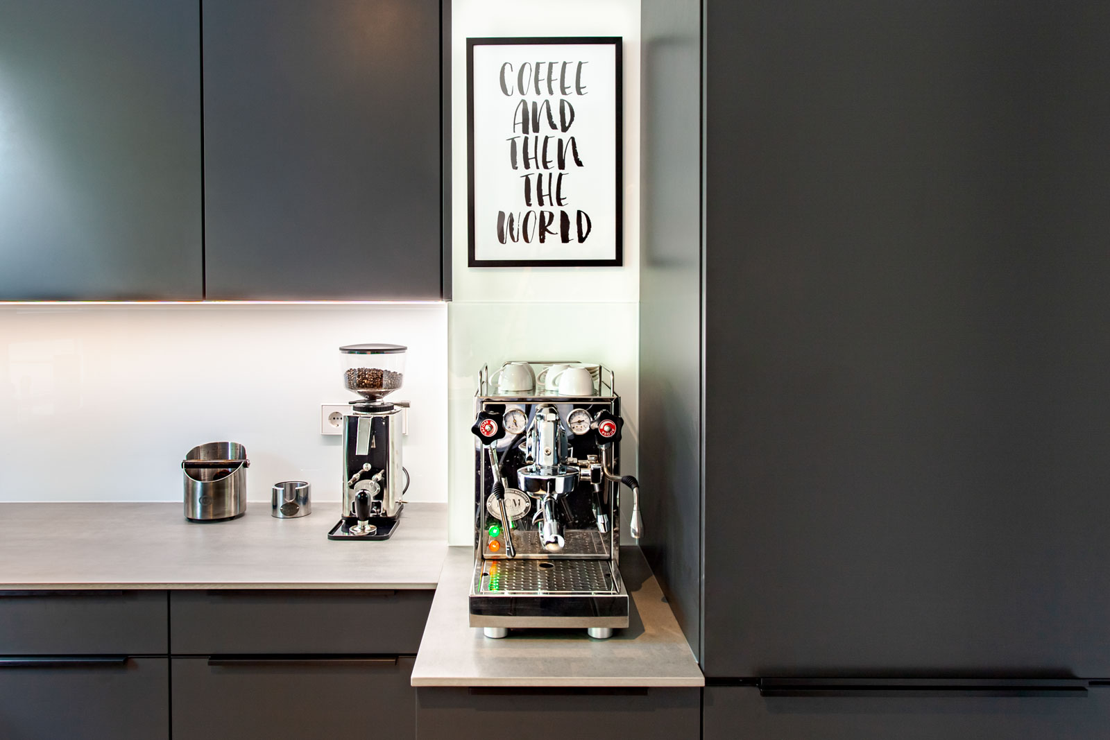 Espressomaschine und Kaffeemühle auf der satinierten Keramik-Arbeitsplatte vor Glasrückwand