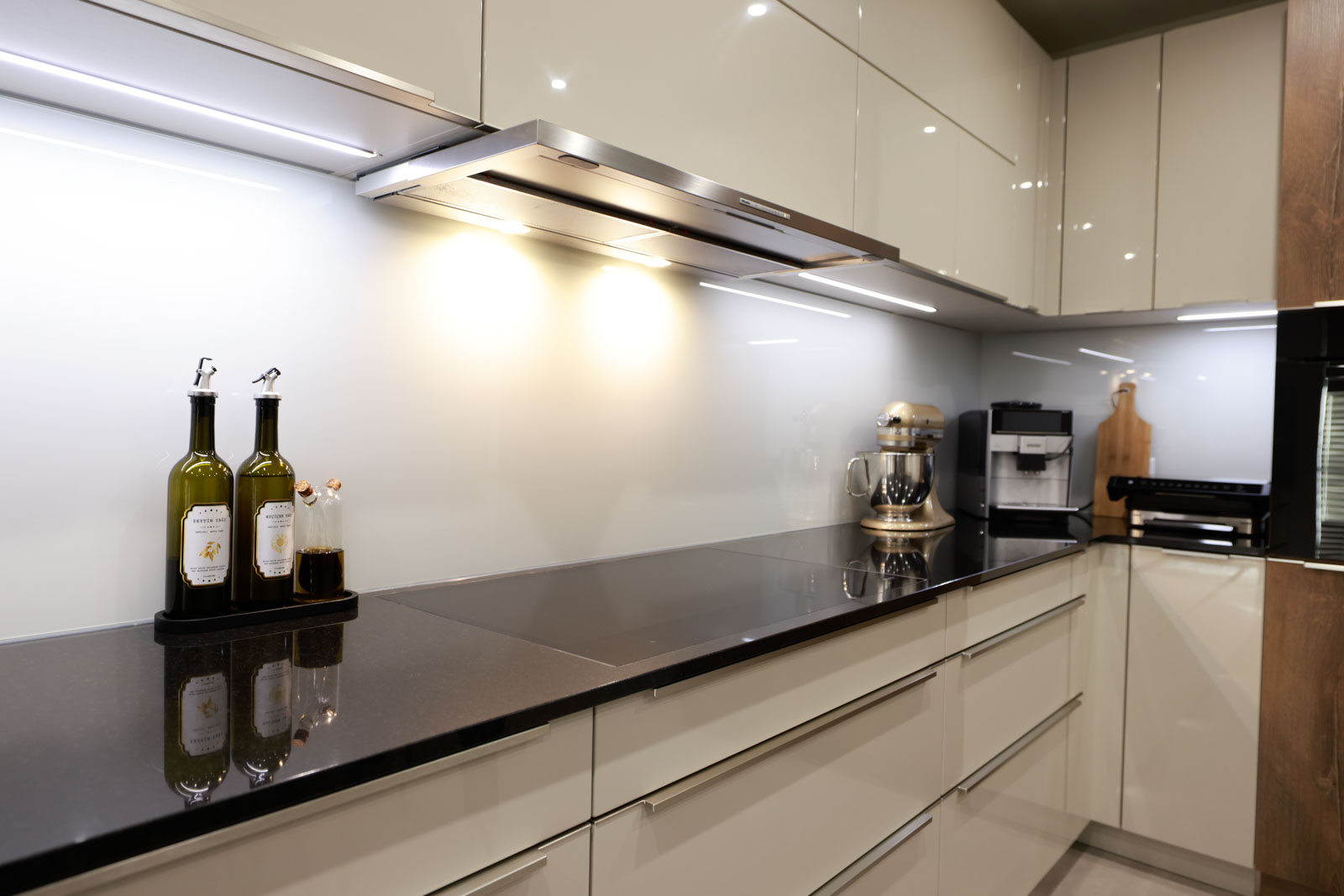 Weiße Glasrückwand White Soft mit indirekter LED-Beleuchtung unter den Hängeschränken und flächenbündigem Kochfeld