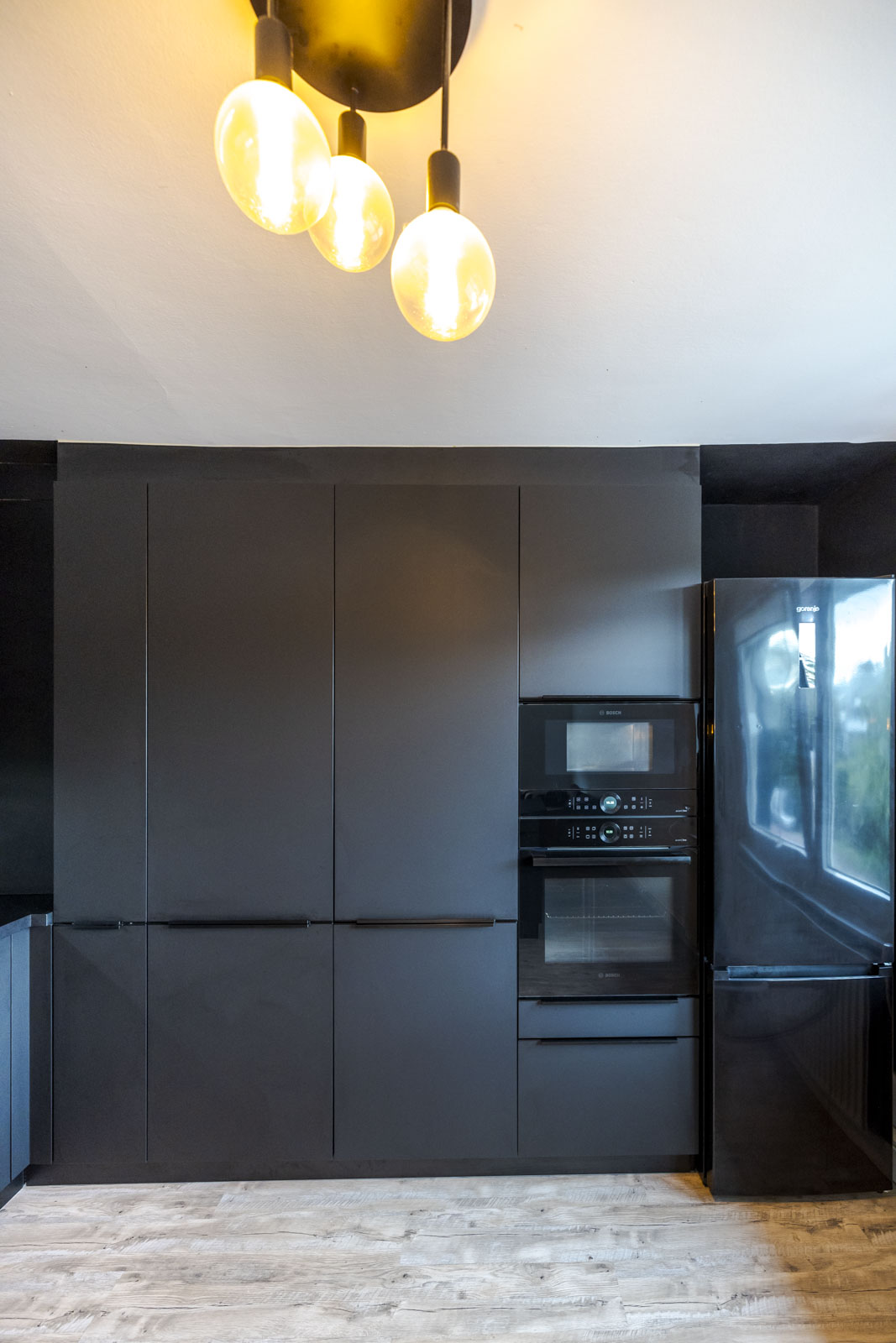 Schwarze Hochschrankwand mit Vorratsschränken, Backofen und Mikrowelle