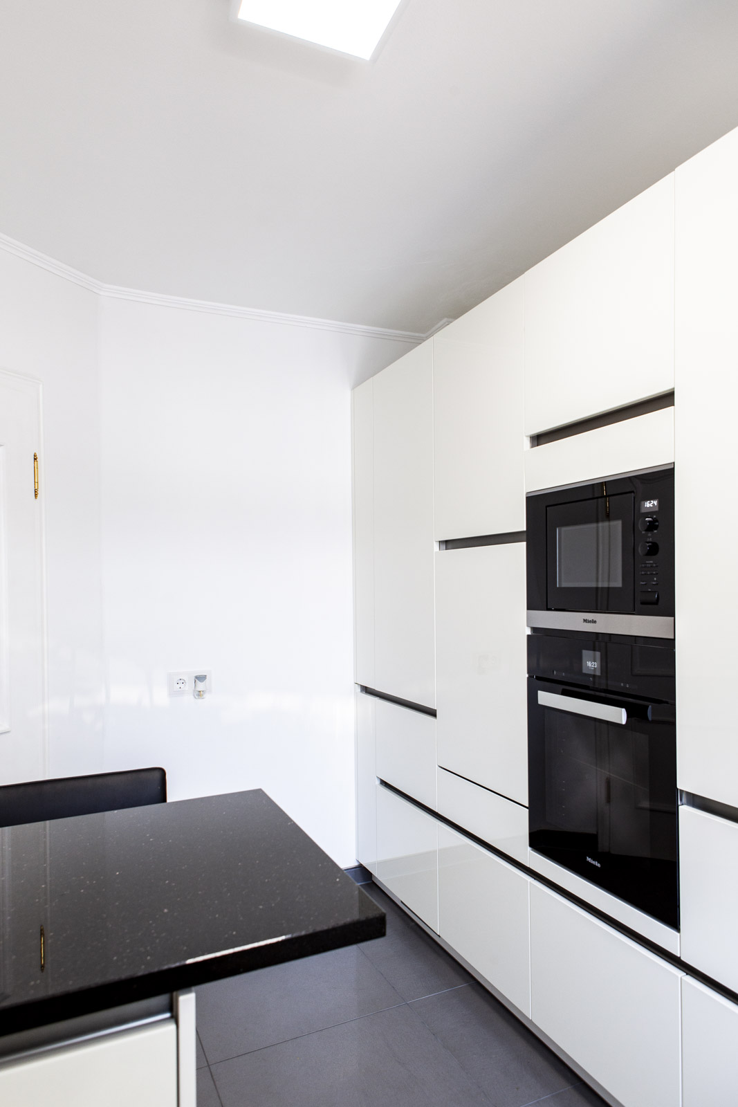 Grifflose weiße Hochglanz-Hochschränke mit eingebauter Miele-Mikrowelle und Backofen
