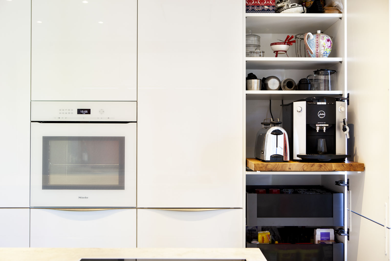 Geöffneter Vorratsschrank mit hölzernem Tablar für Kaffeevollautomat und Toaster