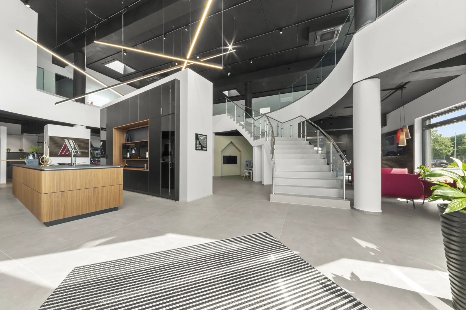 Eingangsbereich des Akbulut Showrooms in Hannover mit geschwungener Treppe zur Galerie