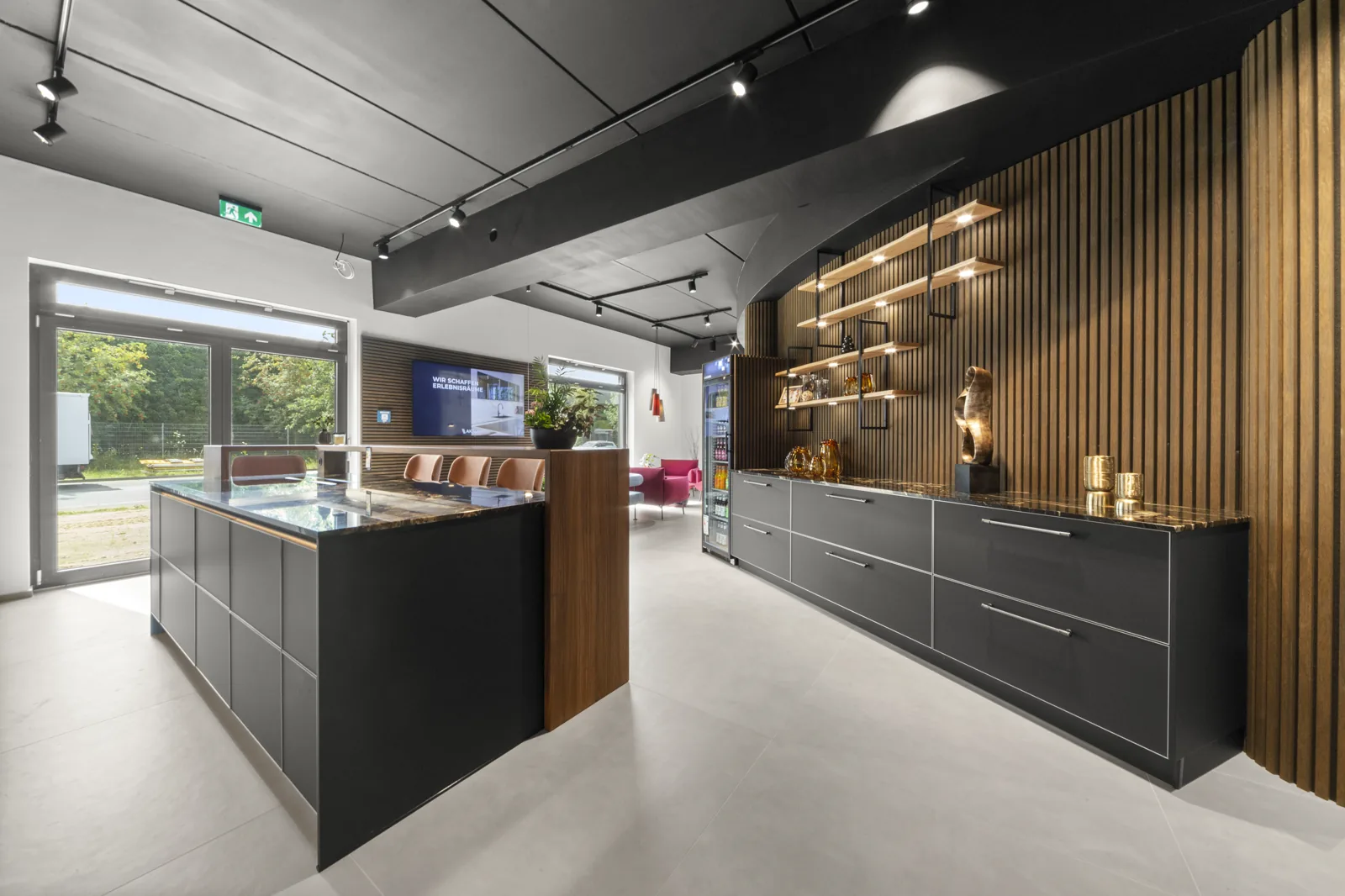 Schwarze Kücheninsel und Schrankzeile vor einer Wand aus Holzlamellen